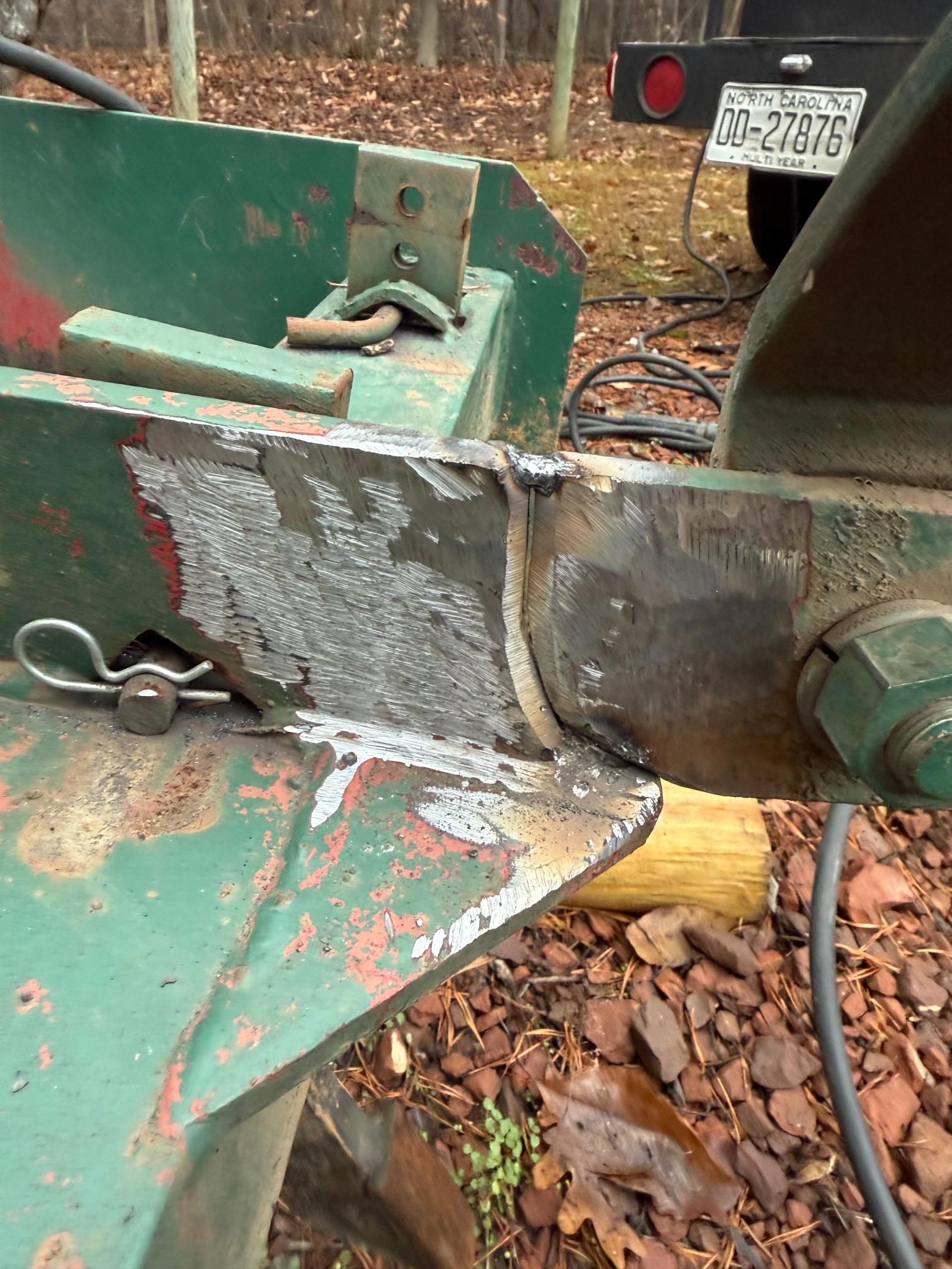 Green agricultural machine's welded joint with a hitch pin and large nut.