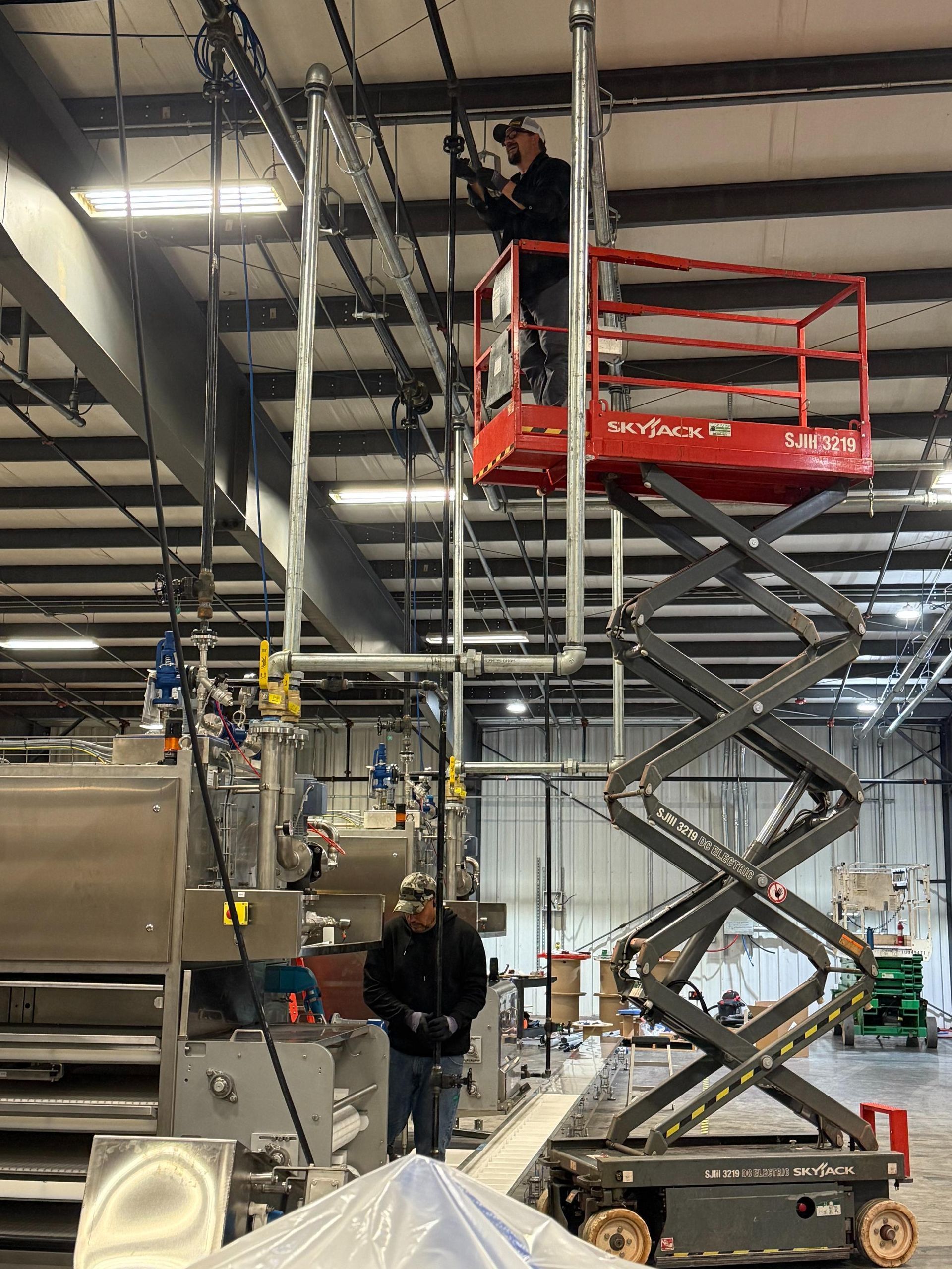 A long metal pipe being worked on in a garage, supported by a pipe stand.