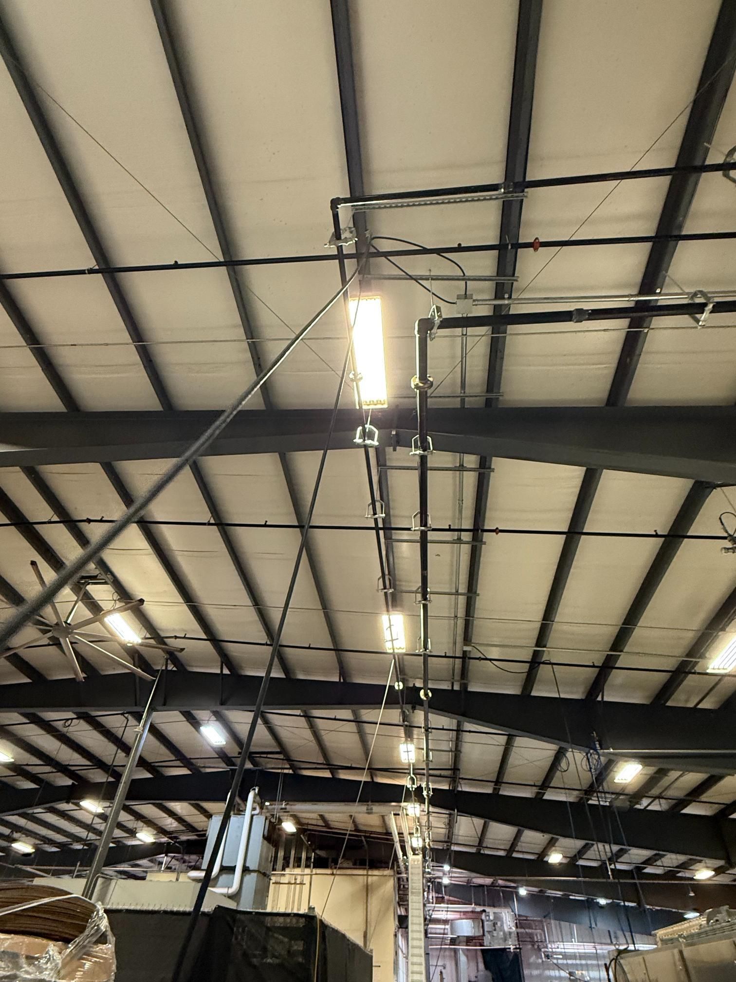 Metal industrial building ceiling with overhead fluorescent lights.