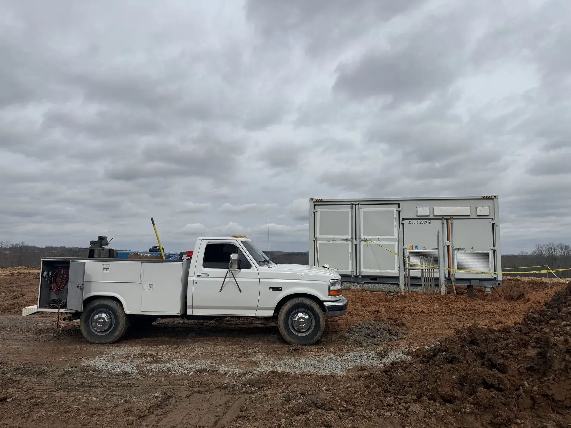 A metal plate held in a vise with metal strips attached. A rusty metal case is in the background.