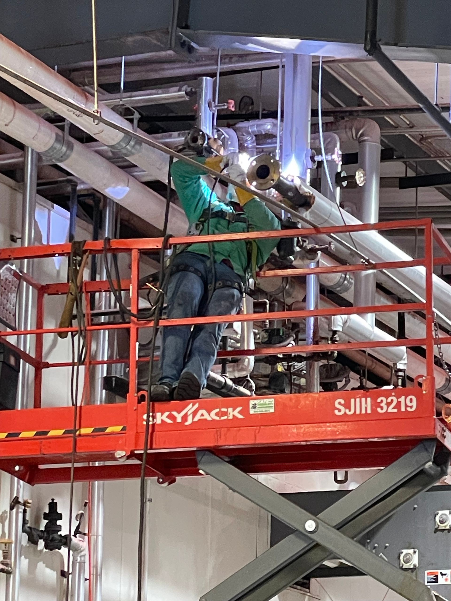 Red welded metal on a trailer component, with a blue spot and outdoor setting.