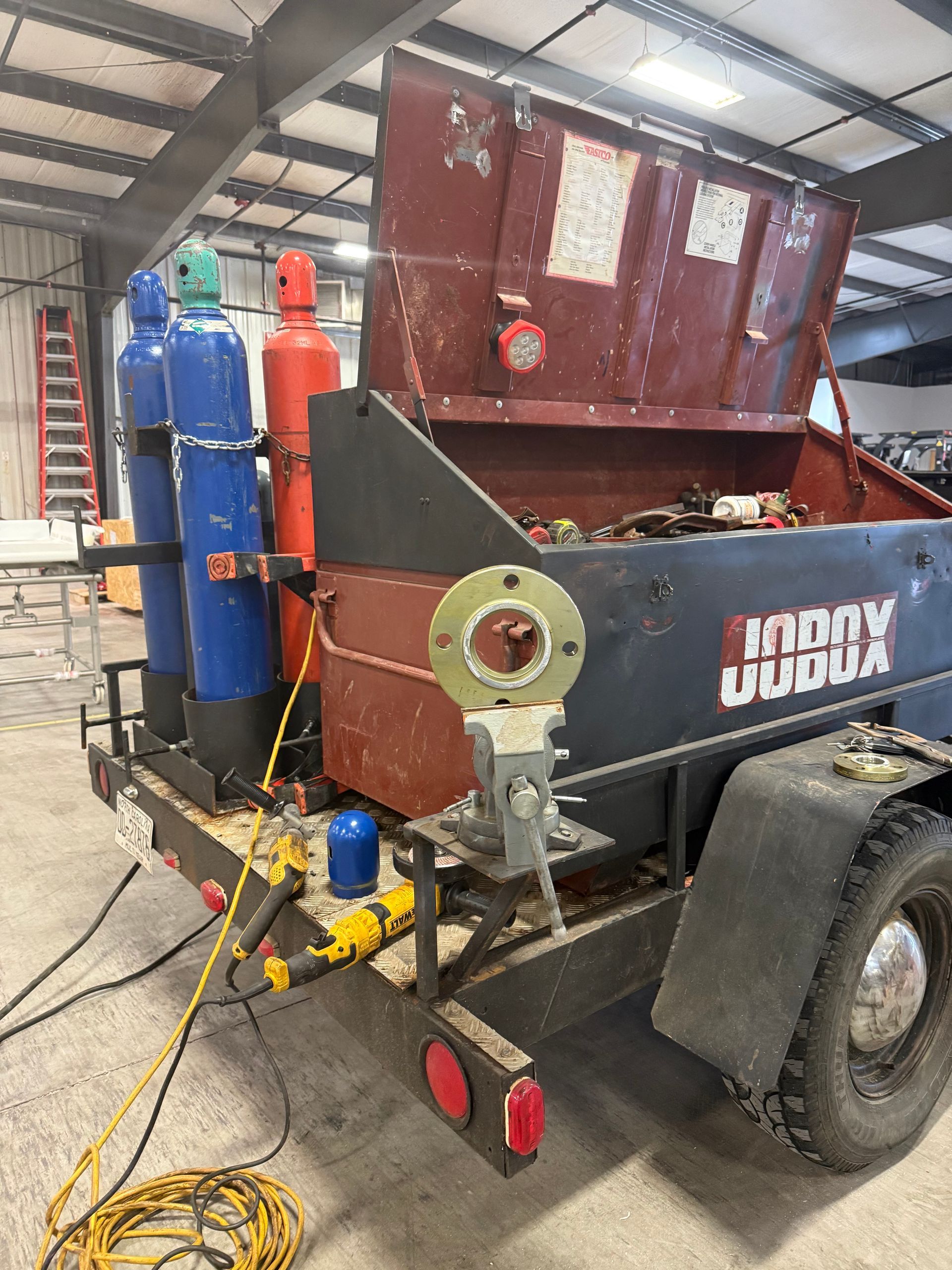 Trailer with three gas tanks, storage compartment, and a welding accessory.