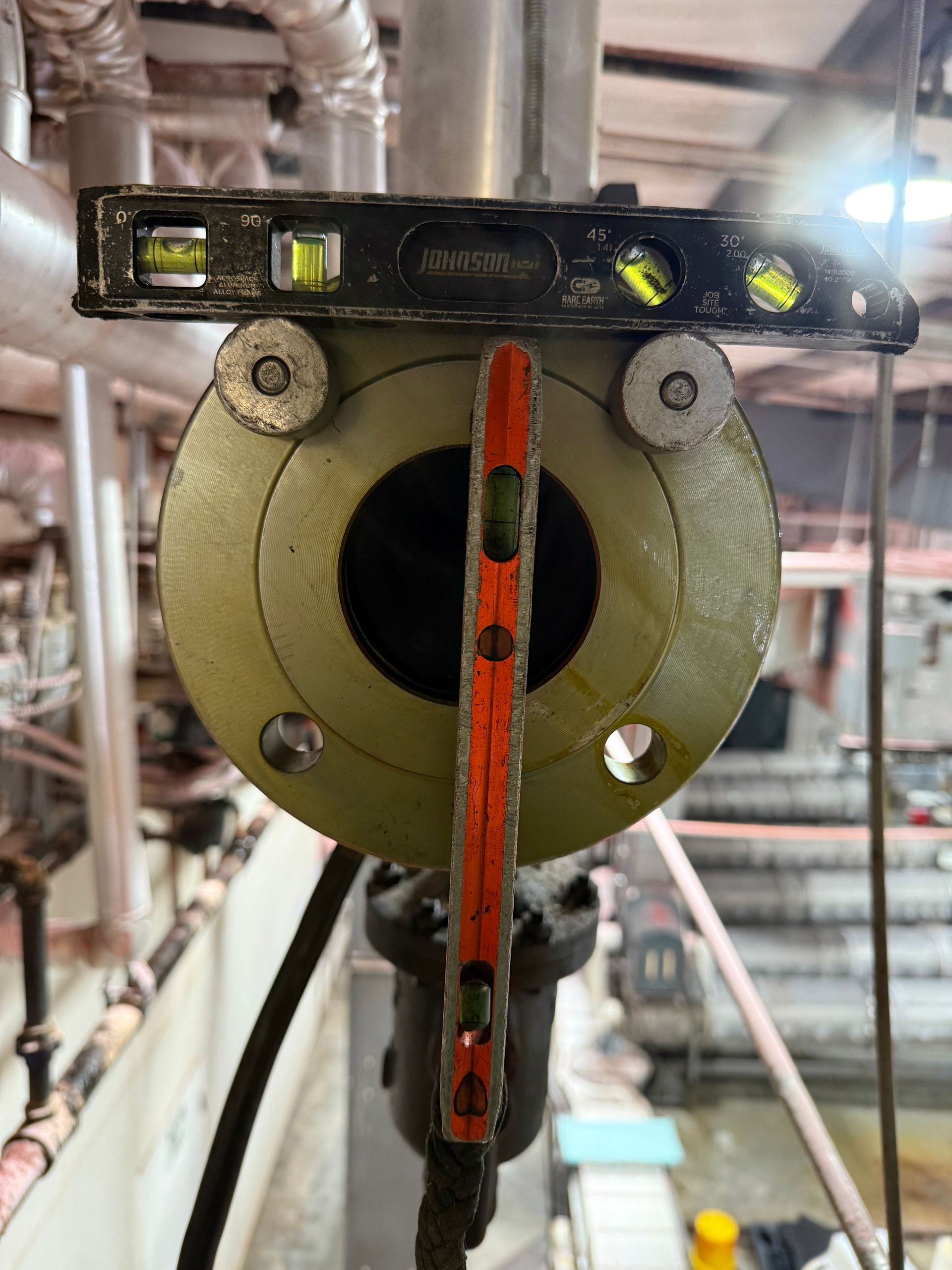 A level placed on a round flange, used for checking alignment in an industrial setting.