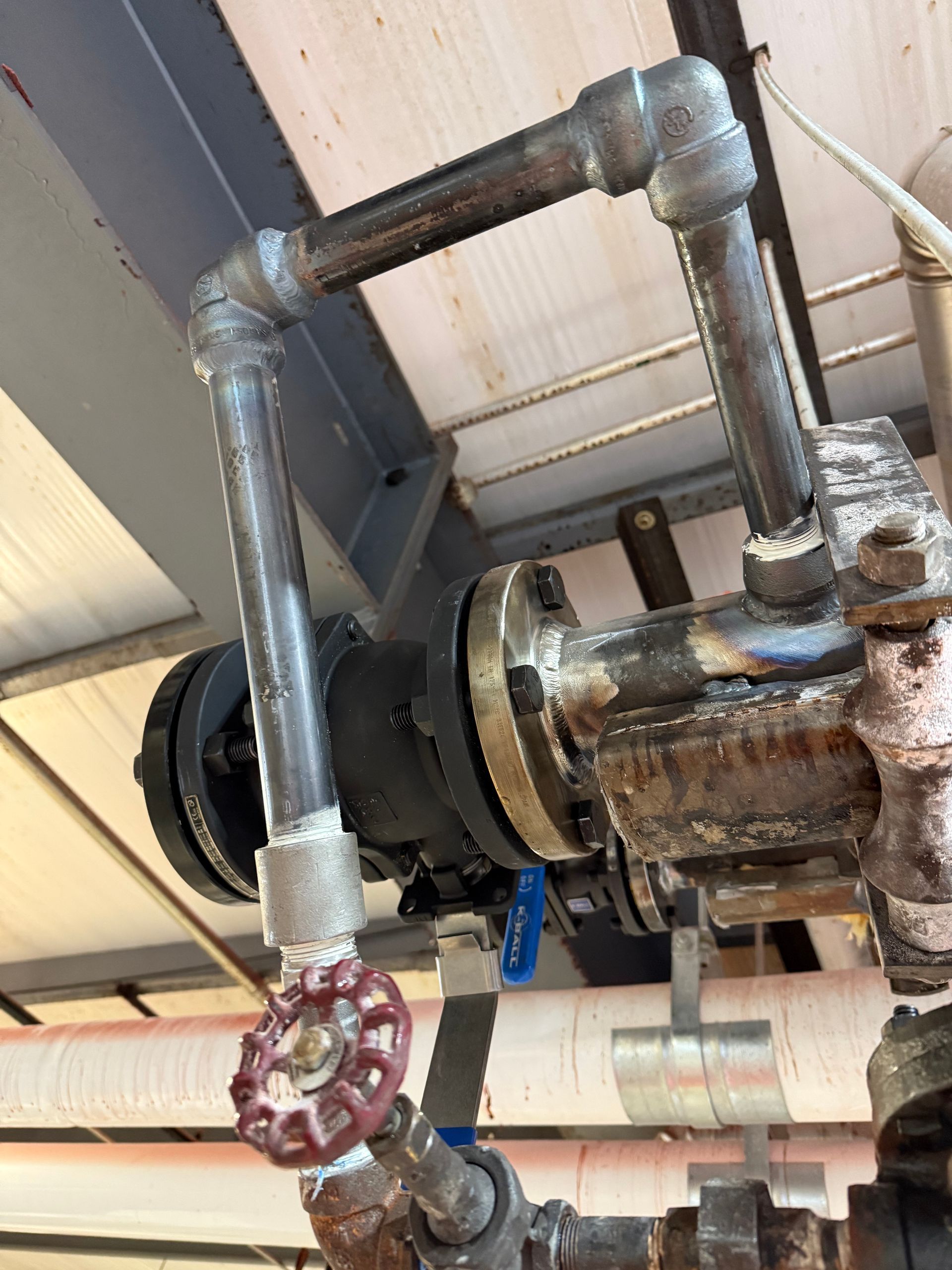 Person on a ladder working inside a garage with equipment including a welding torch and oxygen tank.