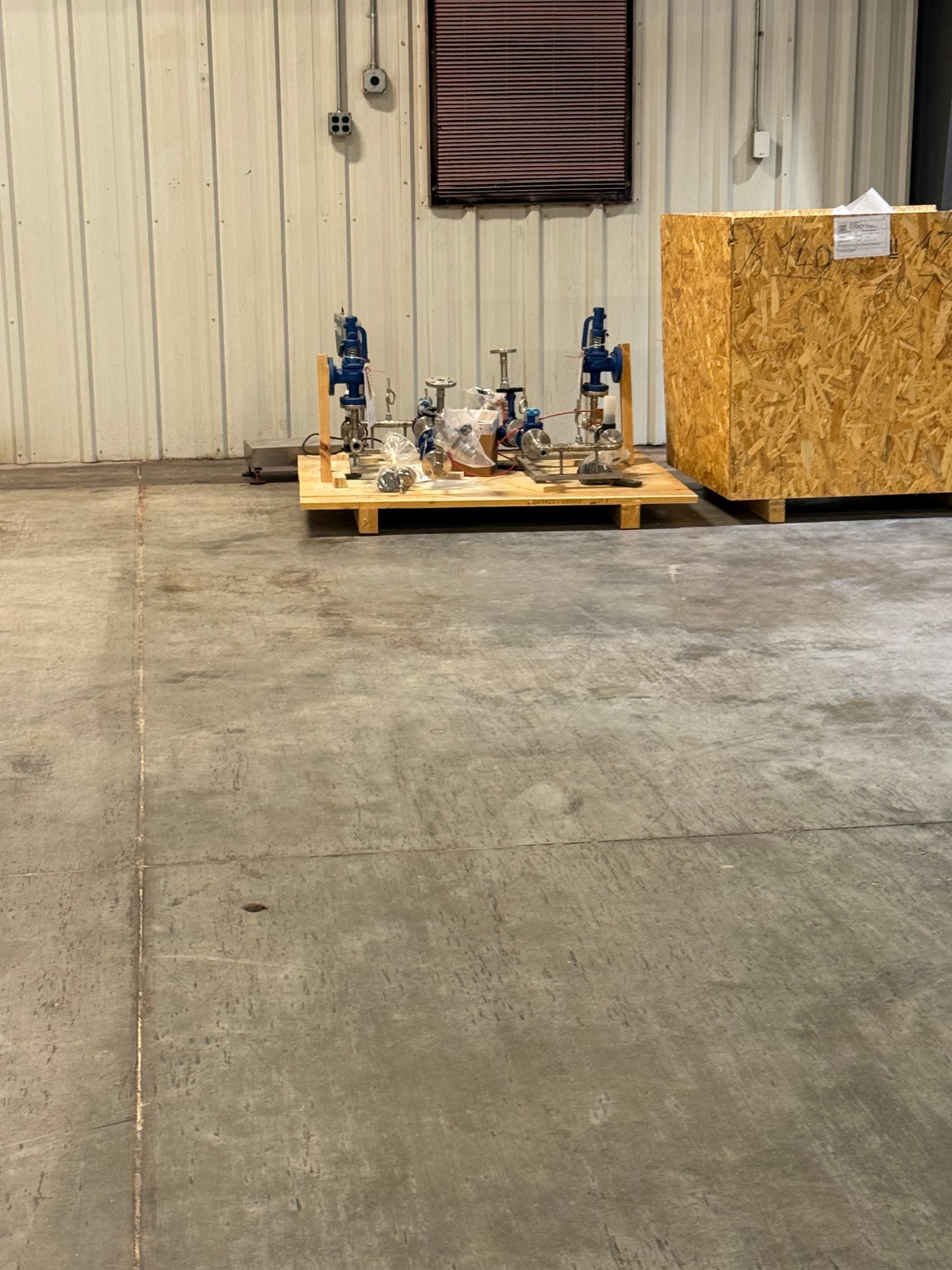 Pallet with industrial equipment, wood crate, and flag in a warehouse.