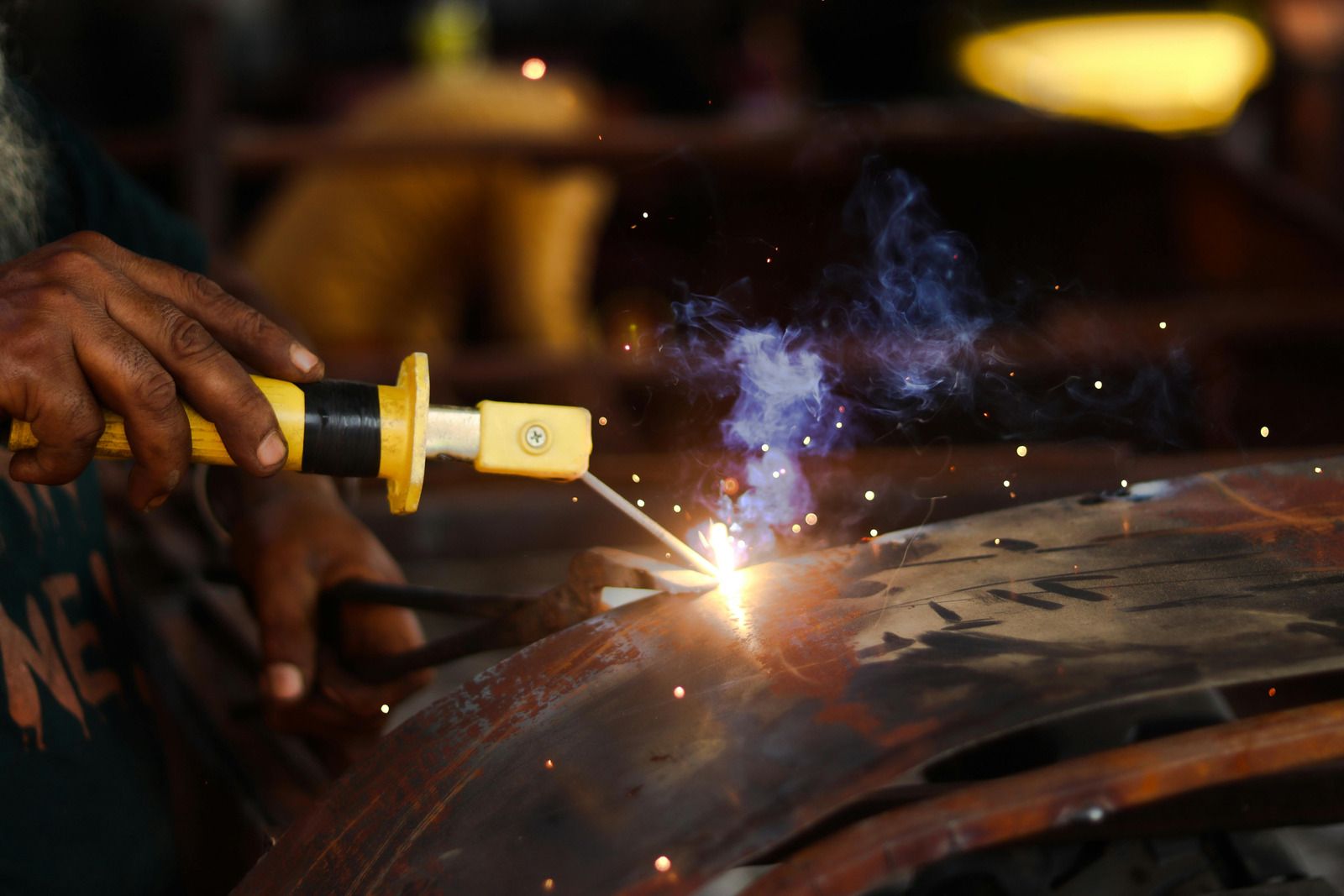 Welder using a torch, creating sparks on metal.