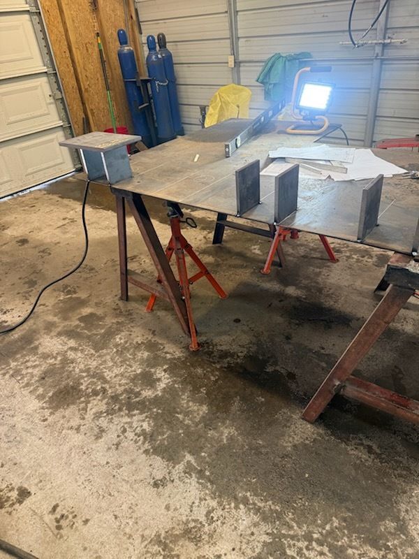 A welding trailer parked next to a building with cables and hoses on the ground.