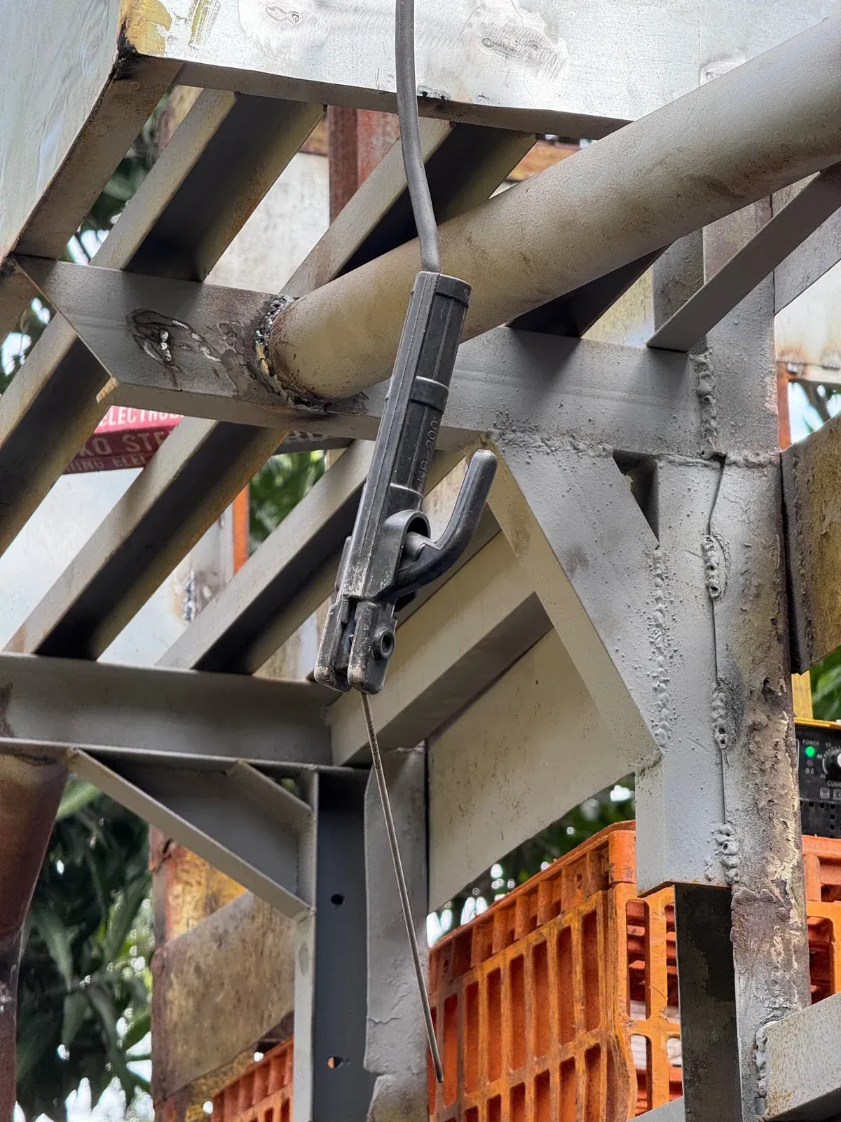 A person uses a drill on a metal bar in a workshop. Sparks and metal shavings are visible.