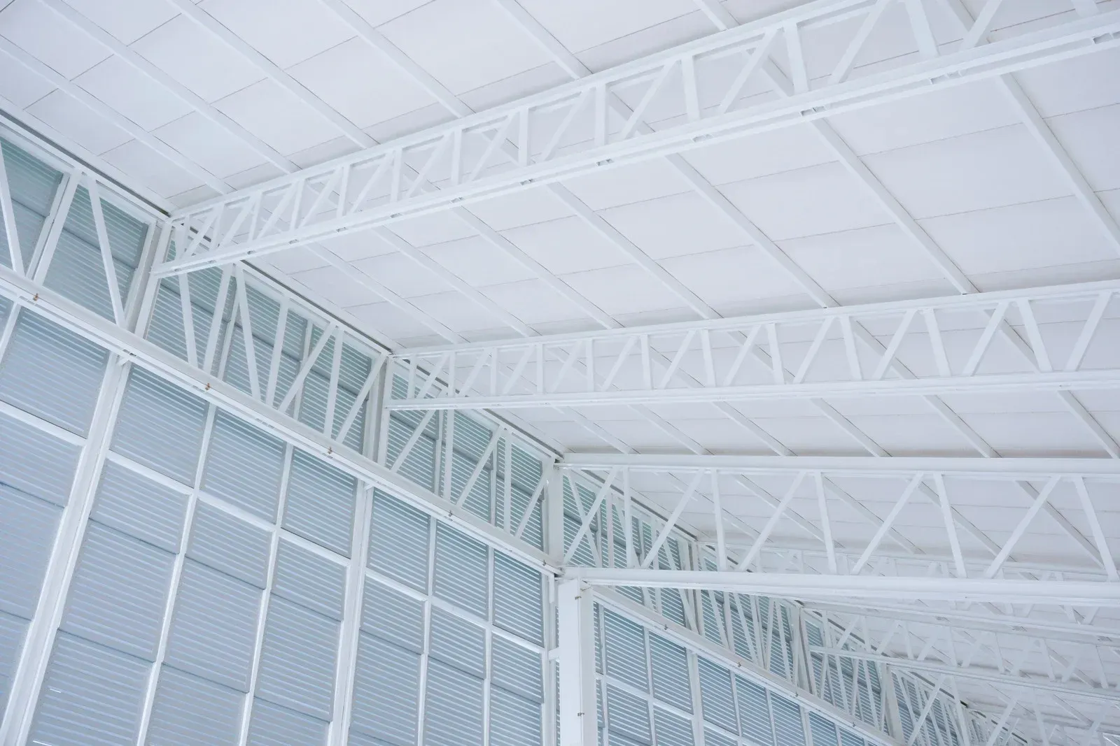 White steel roof trusses and panels inside a building.