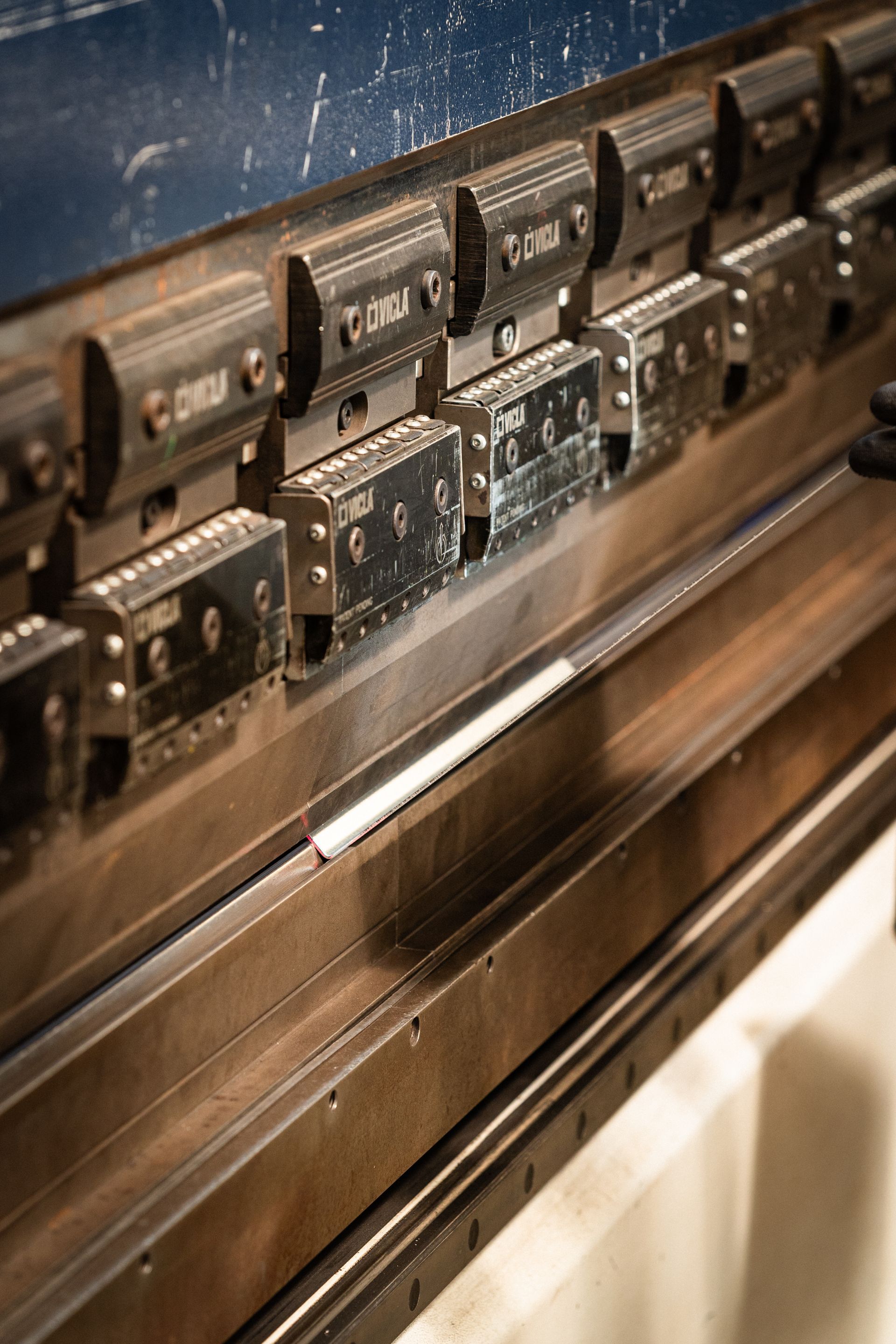 Piegatrice per metalli, con utensili regolabili e lamiera in posizione, pronta per la piegatura.