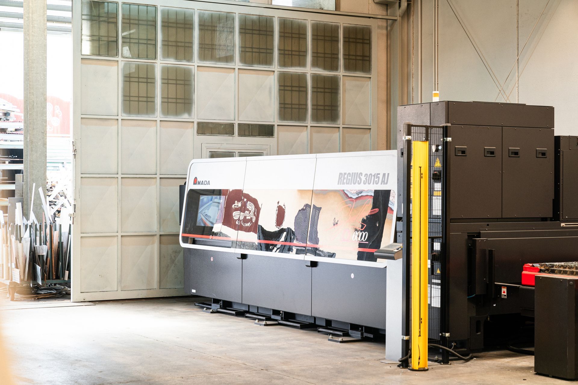 Macchina industriale in un ambiente di fabbrica, con una grande porta scorrevole grigia.