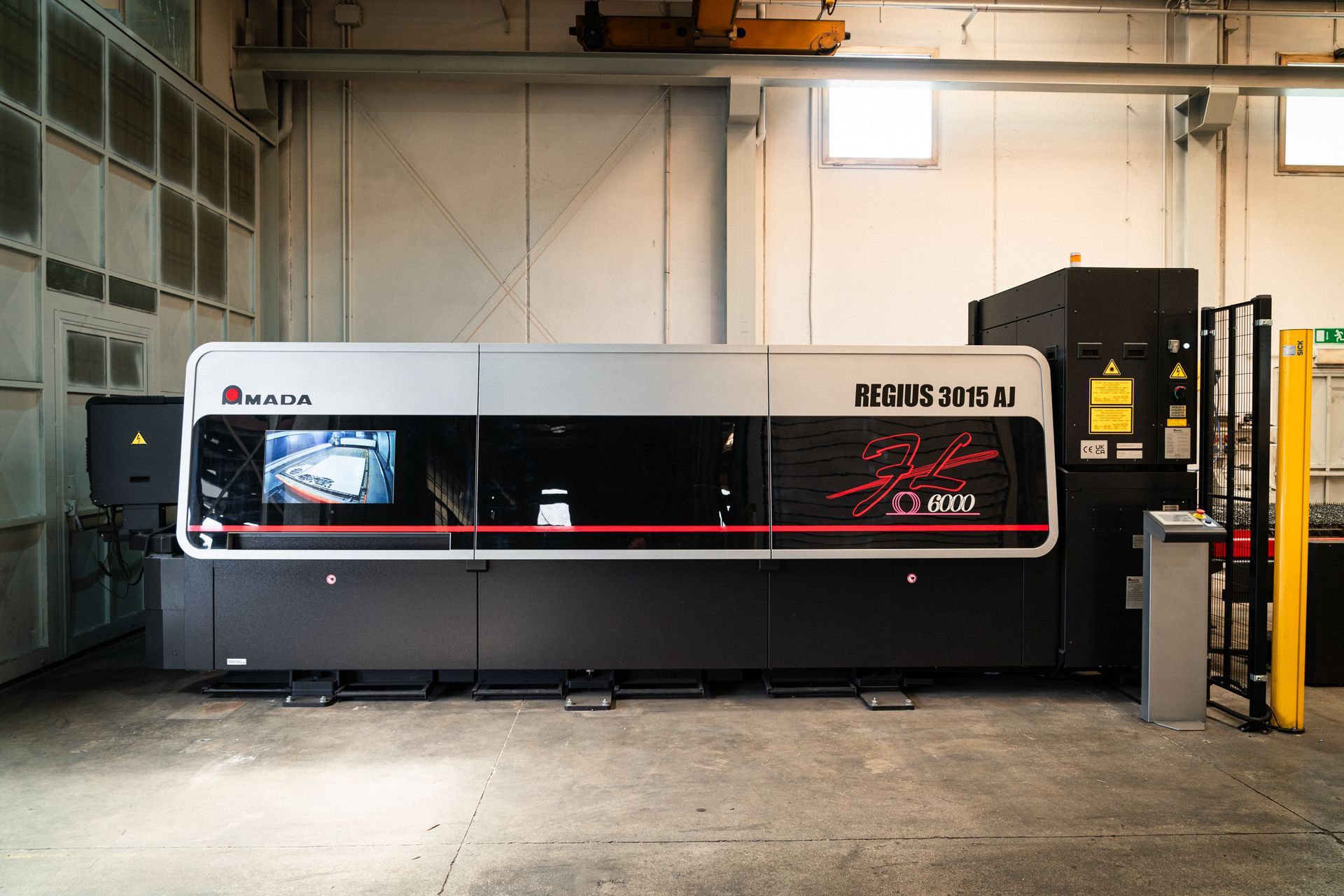 Grande macchina industriale per la lavorazione dei metalli in un ambiente di fabbrica. Combinazione di colori nero, grigio e rosso.