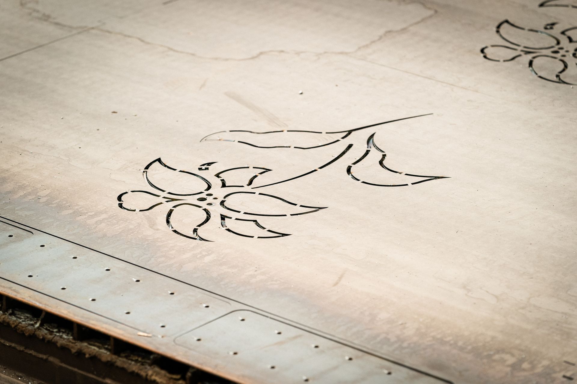 Disegno floreale tagliato al laser su una superficie di legno chiaro, probabilmente a scopo decorativo.