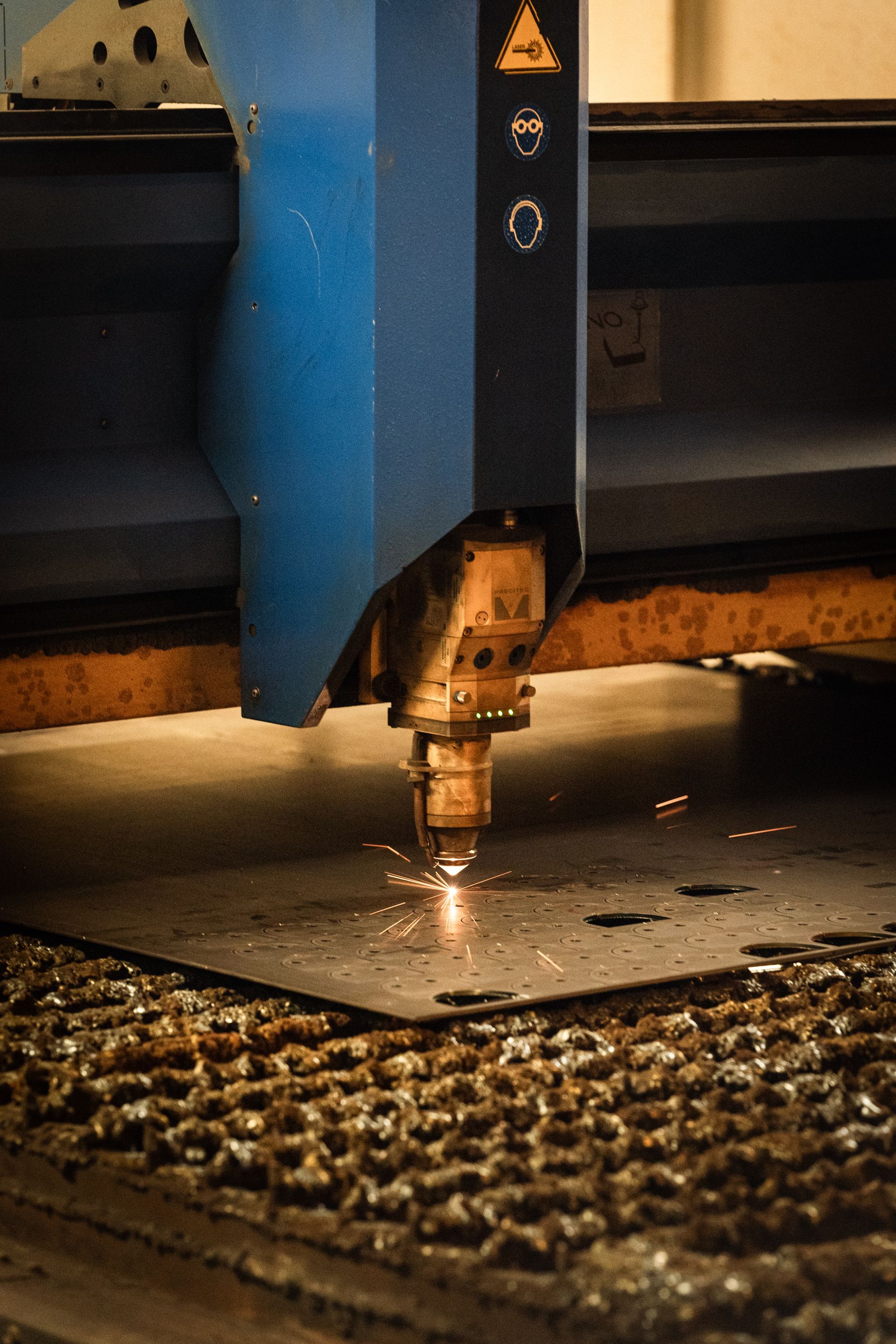 Taglio laser di lamiere, emissione di scintille, ambiente industriale.