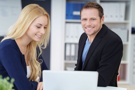 Ein Mann und eine Frau schauen sich einen Laptop an.