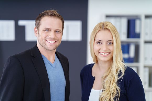 Ein Mann und eine Frau posieren in einem Büro für ein Foto.