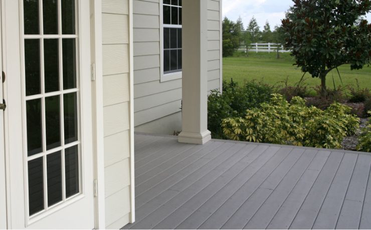 A photo of a deck that is in the backyard of a house. The deck sits low to the ground so it does not have a railing installed.