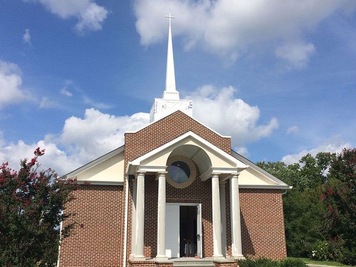 A church with a steeple and a cross on top of it.