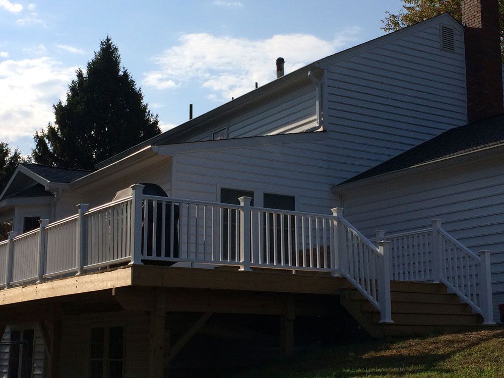 A white house with a wooden deck and white railing
