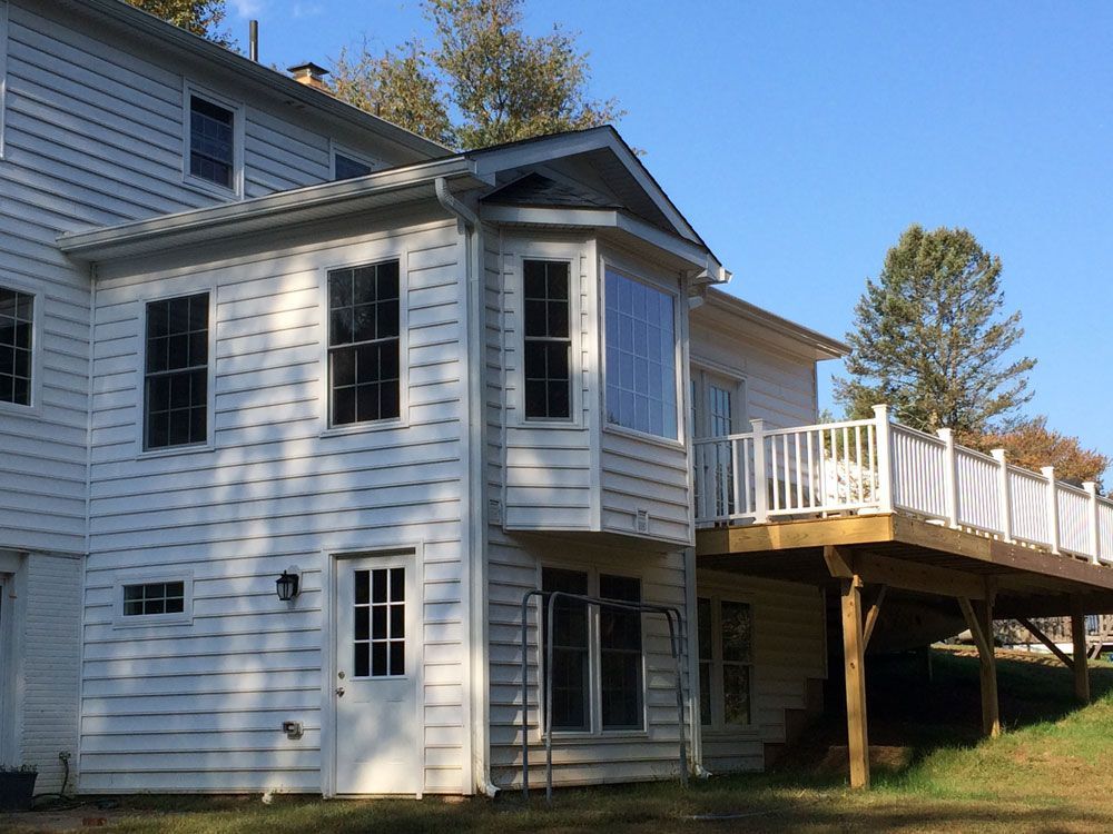 The back of a white house with a large deck.