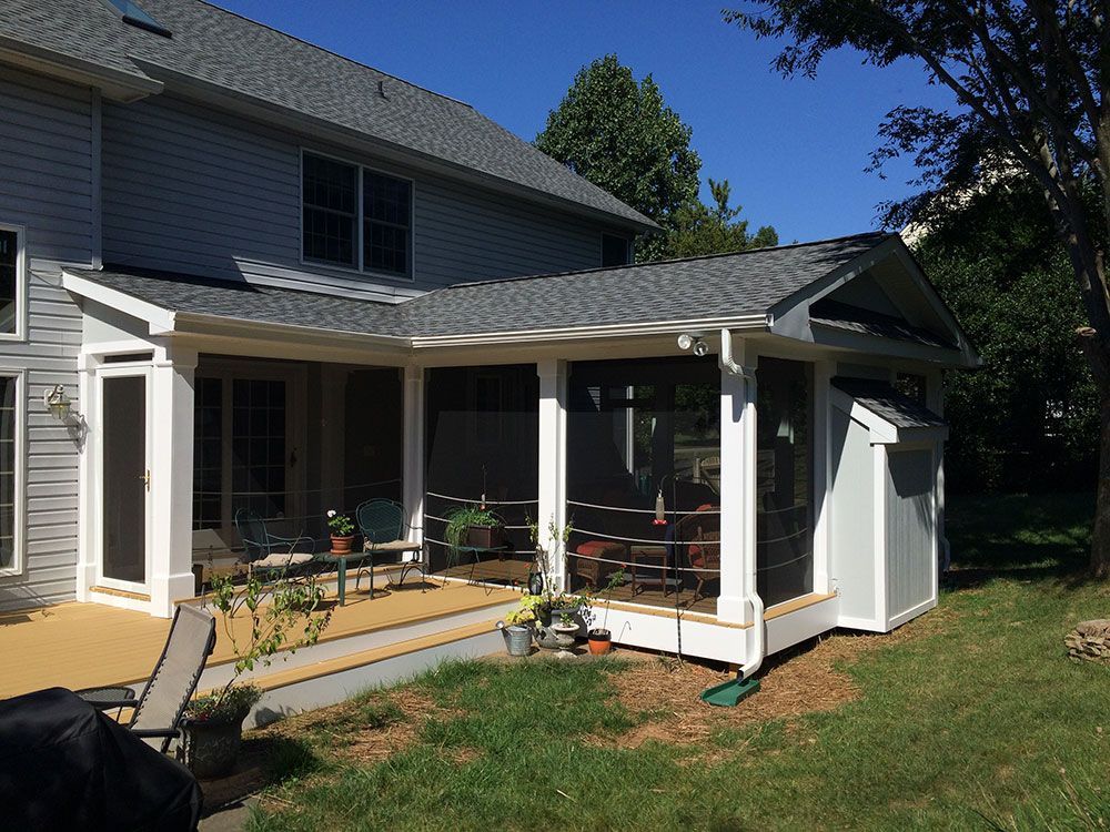 A screened in porch in the backyard of a house