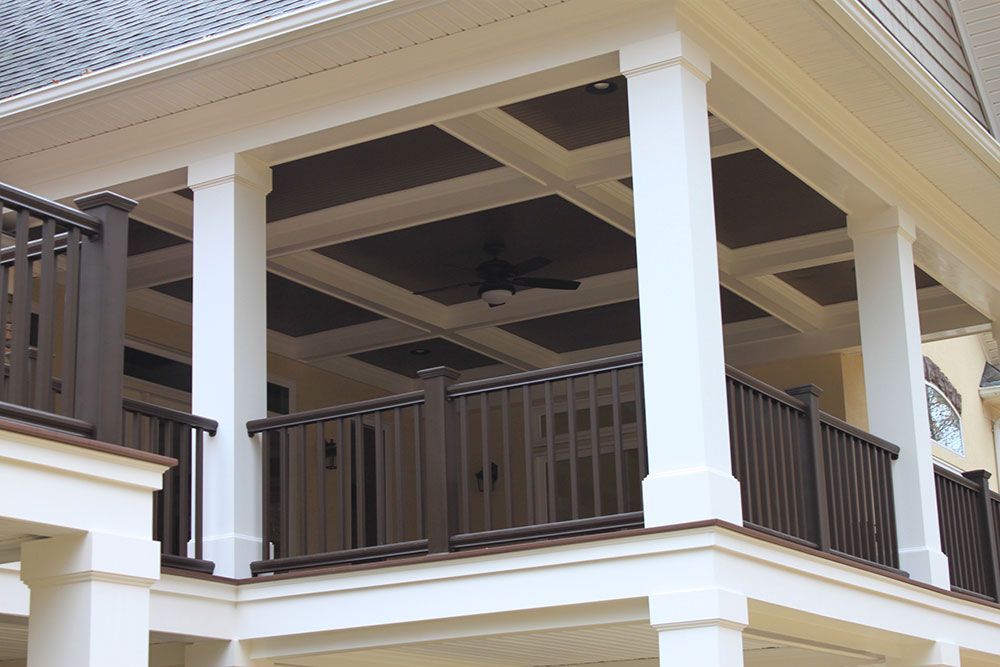 A balcony with columns and a ceiling fan on it