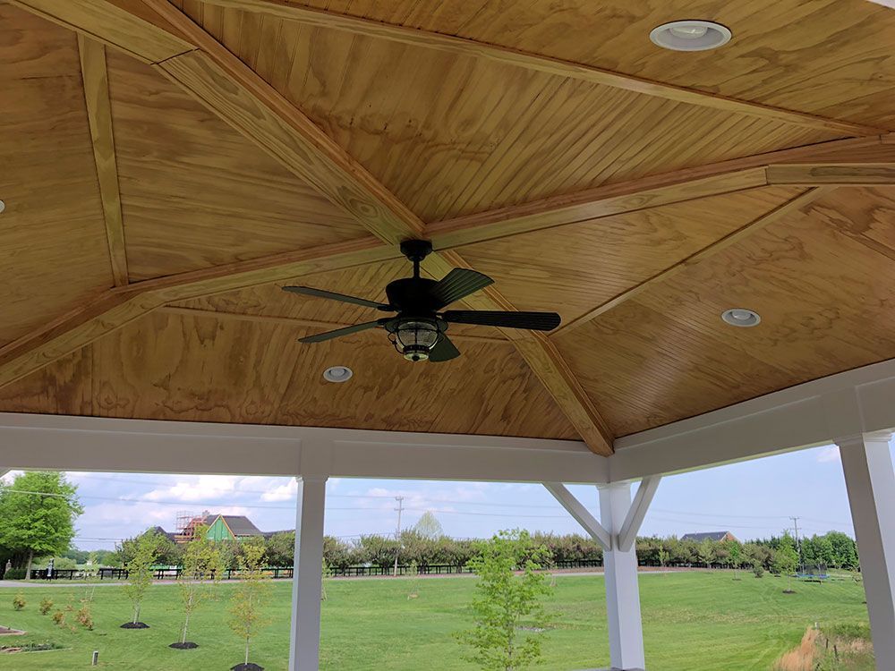 A ceiling fan is hanging from the ceiling of a gazebo.