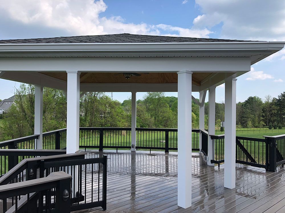 A large deck with a gazebo and a black railing.