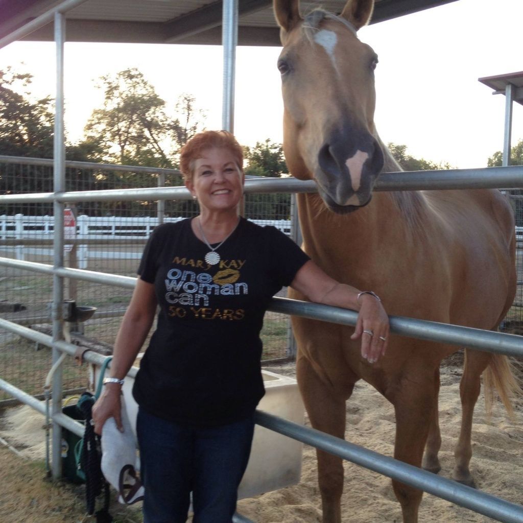 A woman wearing a one woman can campaign t-shirt stands next to a horse