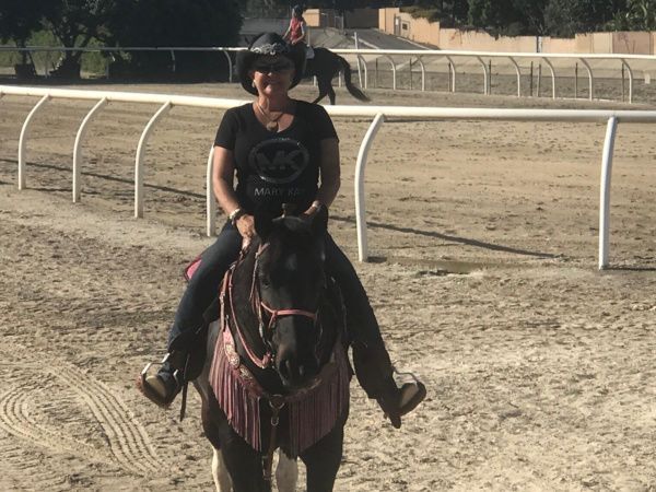 A woman is riding a horse on a dirt track