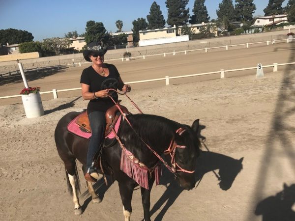 A woman in a cowboy hat is riding a black horse