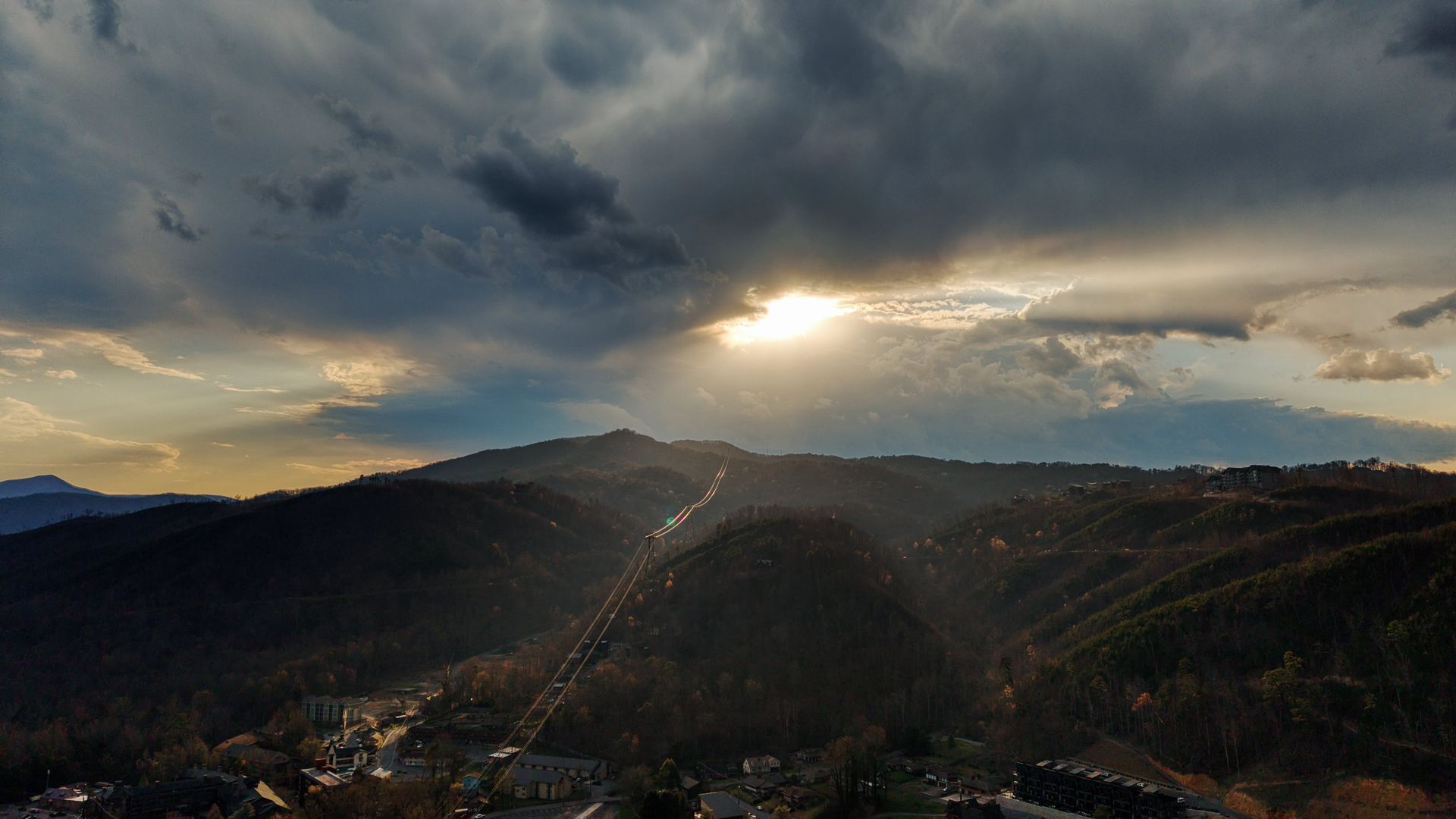 Sunlit mountain valley under dark storm clouds at sunset