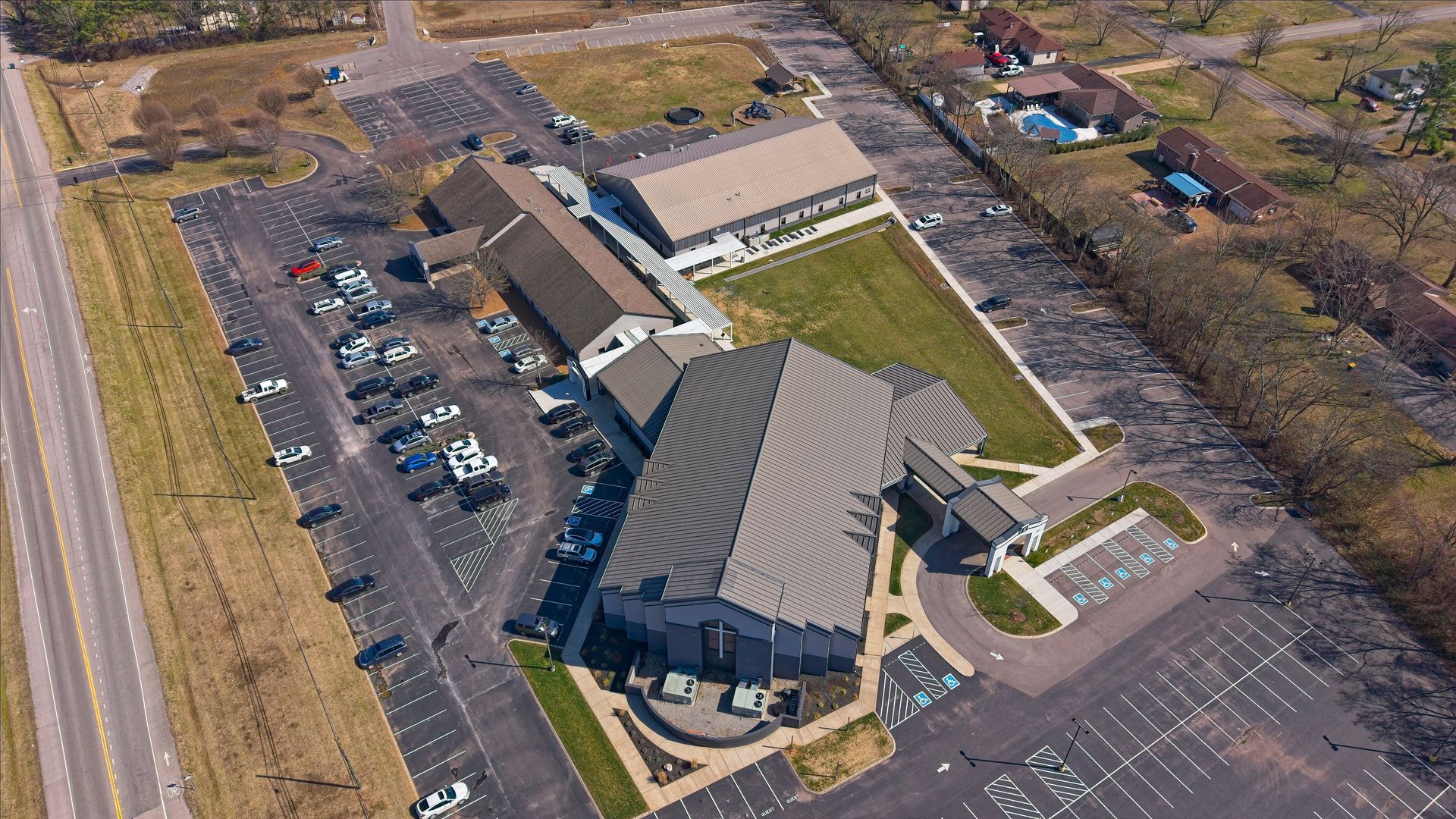 Aerial view of a large building with parking lots and surrounding fields on a sunny day