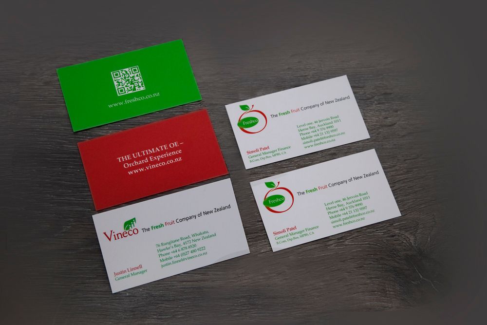 Business cards of various colors with a company logo on a gray surface.
