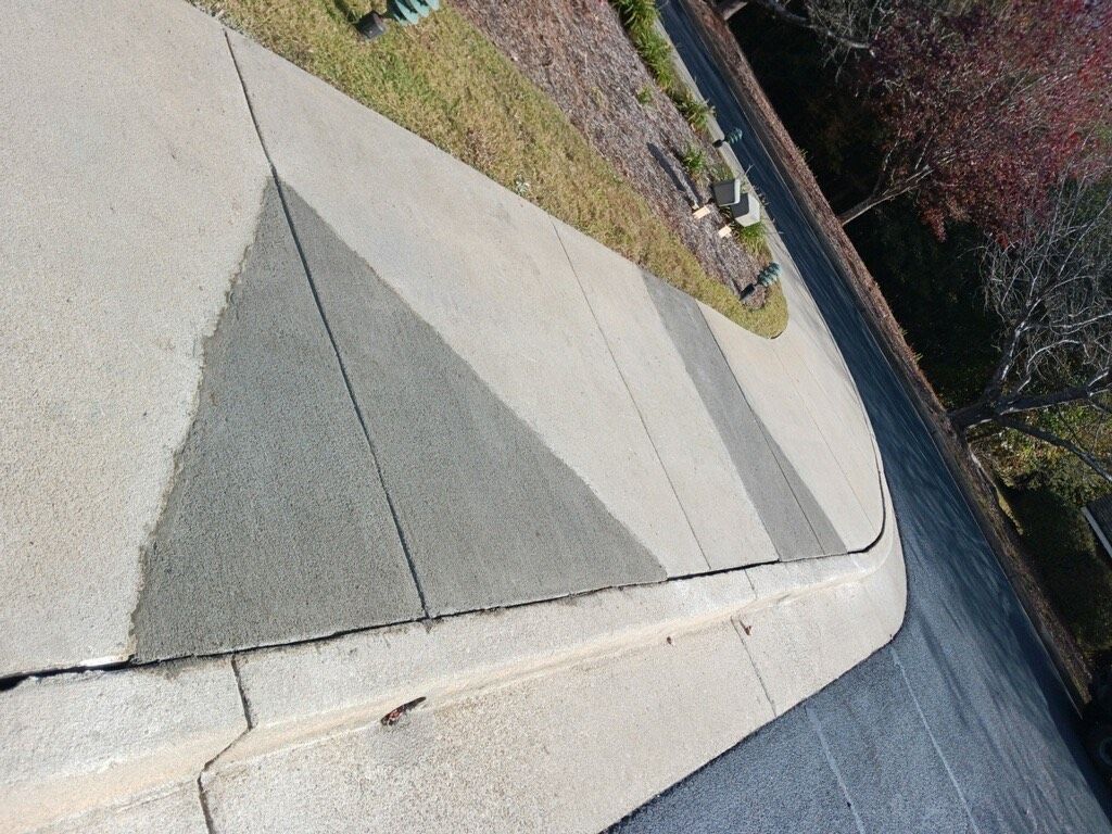 Concrete sidewalk with gray and light gray triangular pattern, next to a curb and grass.