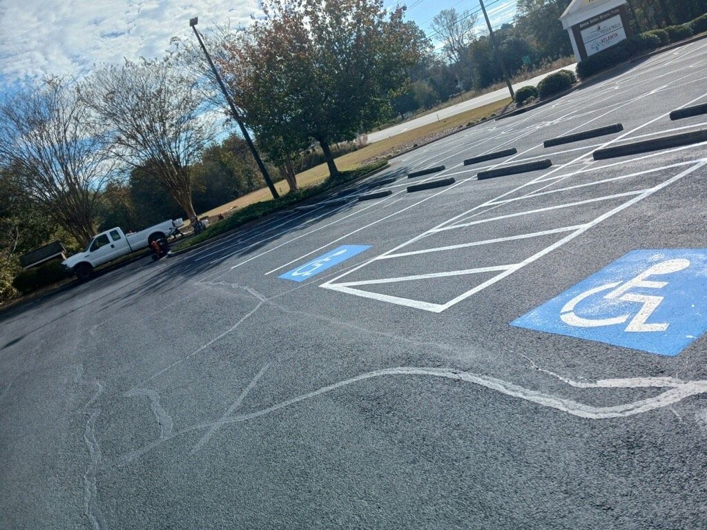 Parking lot with blue handicap parking symbols; white pickup truck parked to the left.