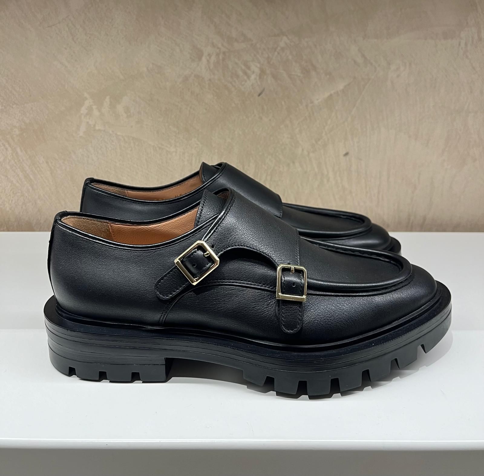 Un paio di scarpe bianche con cinturini neri su un tavolo.marchi