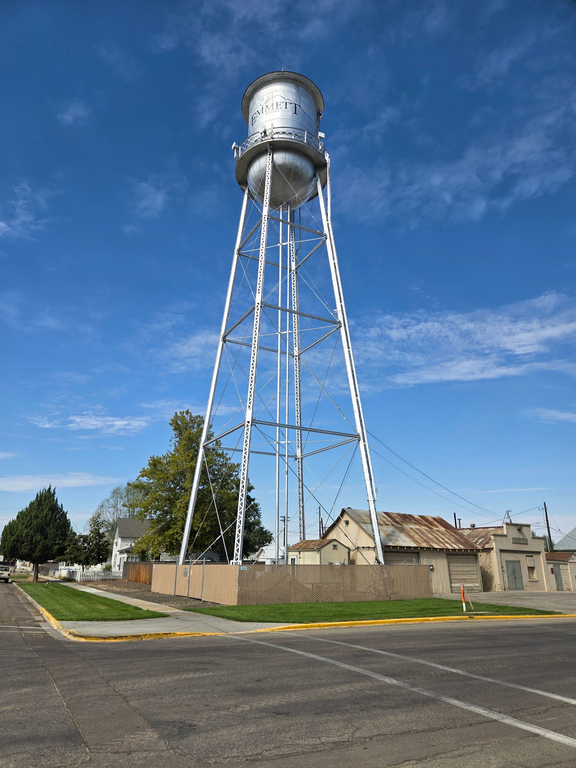 Water tower, tall white metal structure, against blue sky.