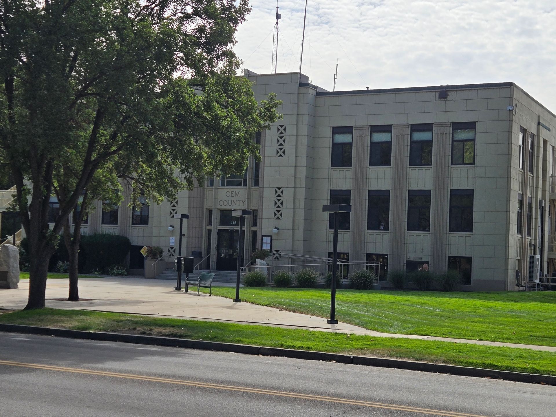 Stone building with entrance, sign, and multiple dark windows, set on a green lawn with a tree.