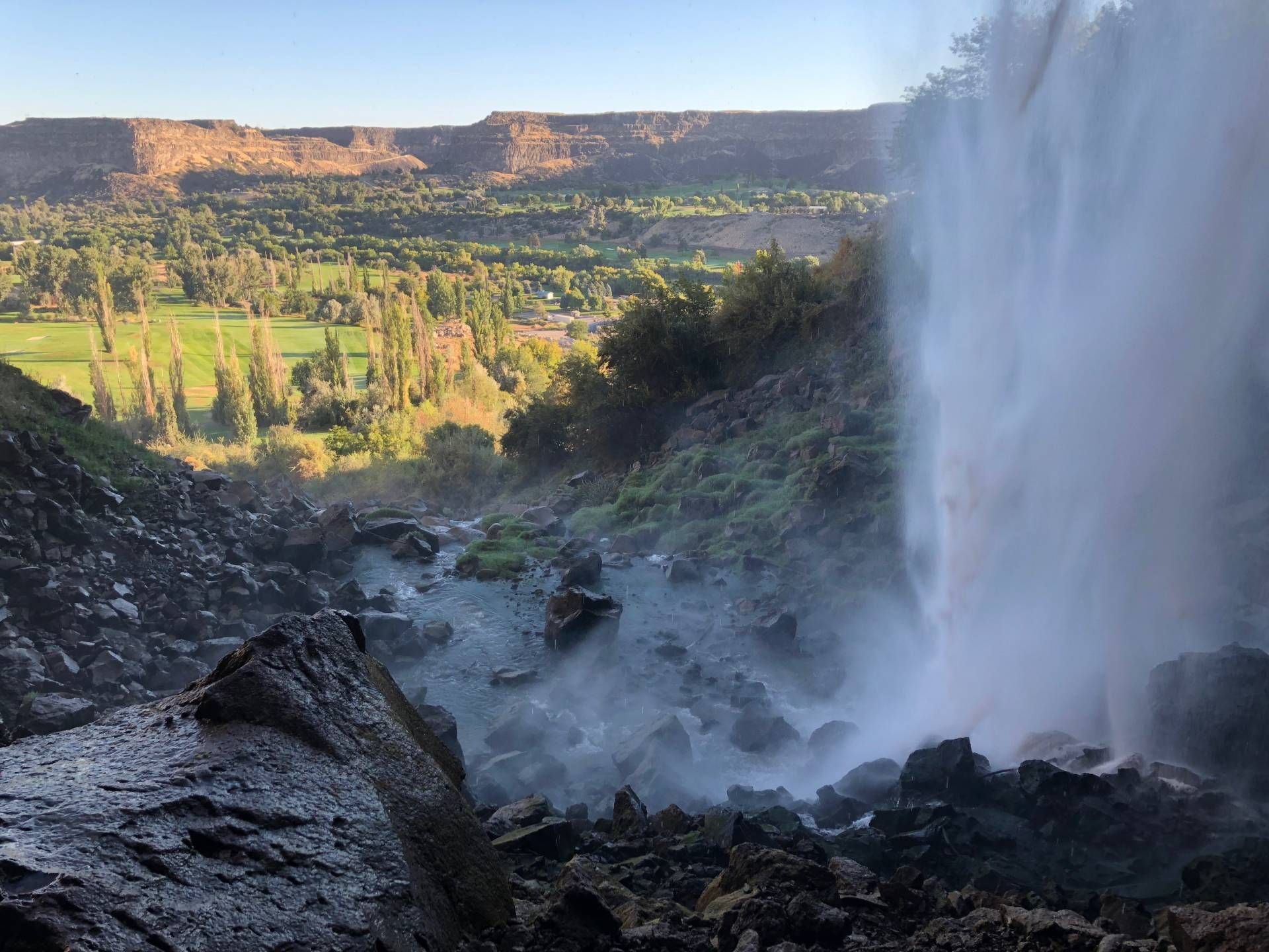 Waterfall cascading into rocky terrain with a valley view.