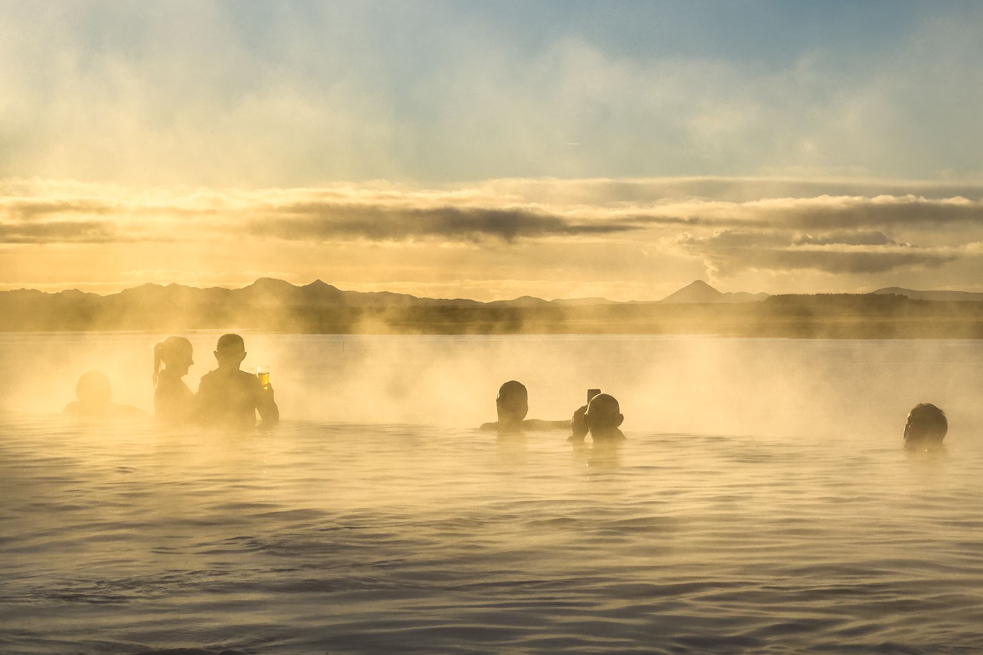 Swimmers in a misty lake at sunrise, with golden light reflecting on calm water