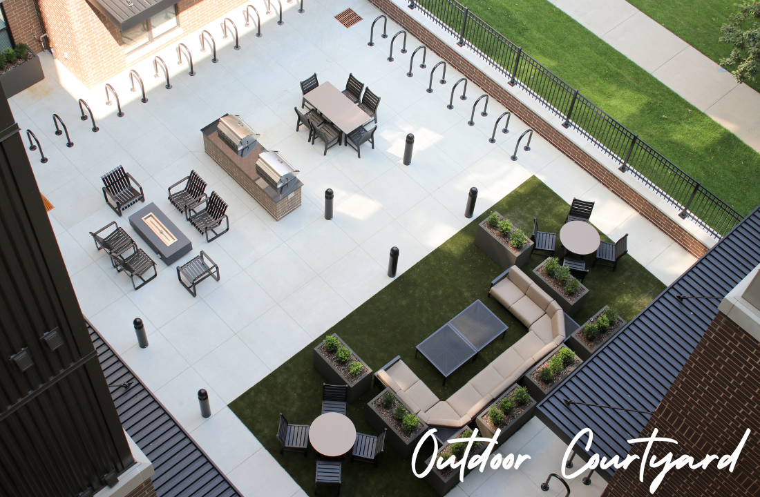 Outdoor courtyard with beige sectional sofa, black tables, and artificial grass.
