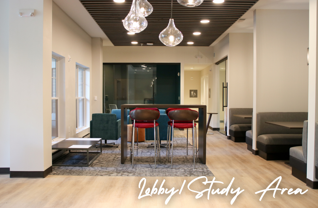 Lobby/study area with tables, chairs, and lighting. Windows on the left. Booth seating on the right.