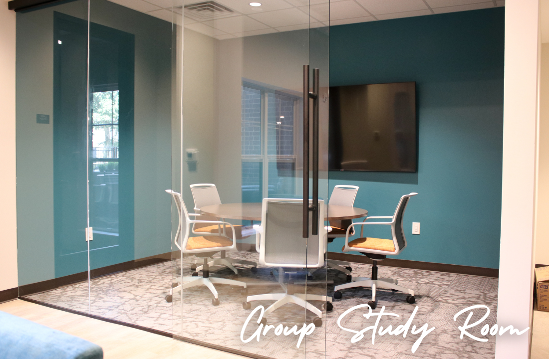 A group study room with a round table, chairs, and a TV; teal and white walls.