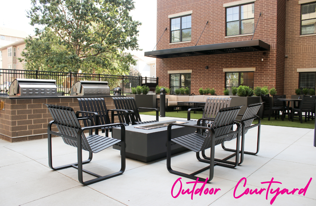 Outdoor courtyard with grills, seating around a fire pit, and building backdrop.
