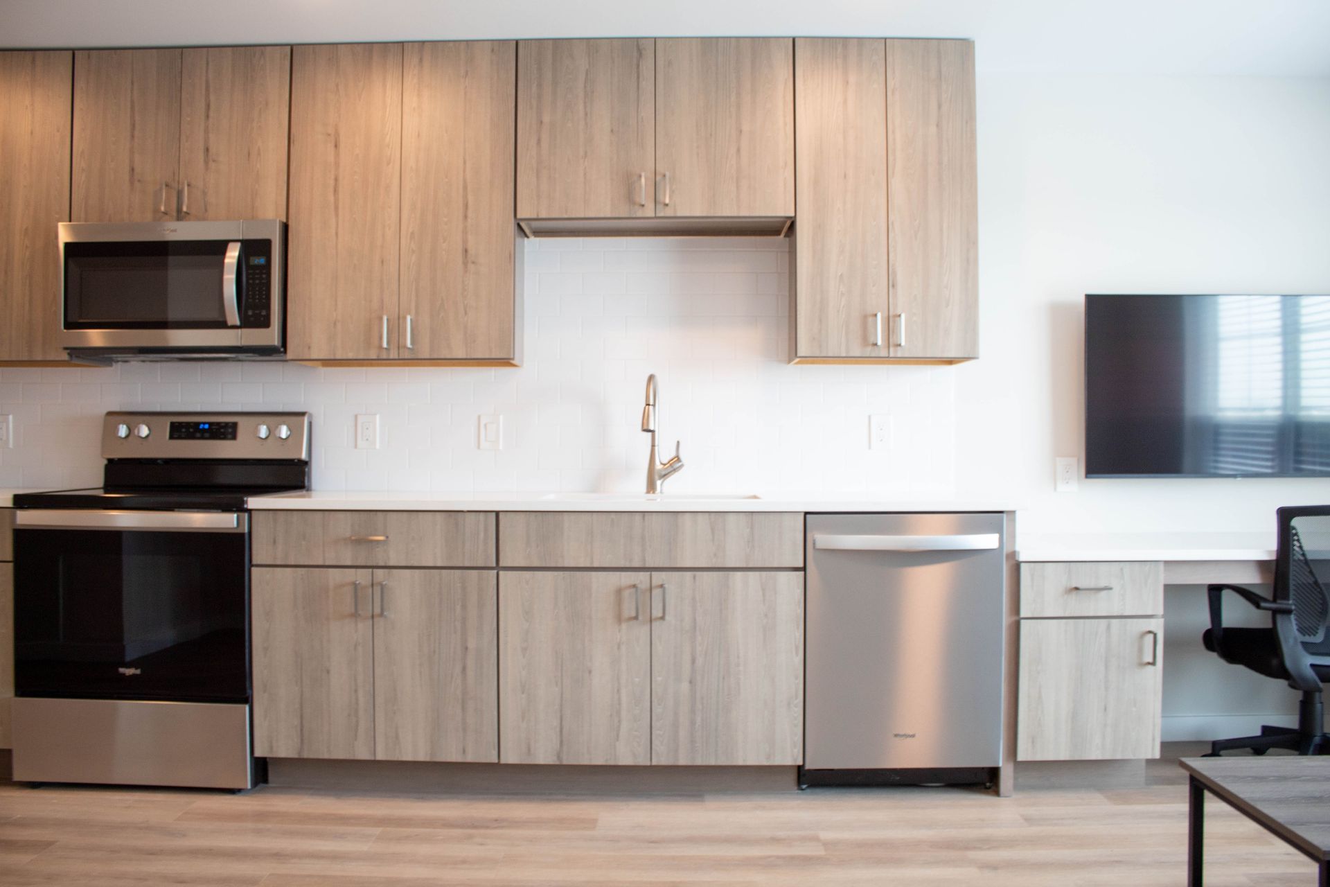 Modern kitchen with wooden cabinets, stainless steel appliances, and a white countertop.