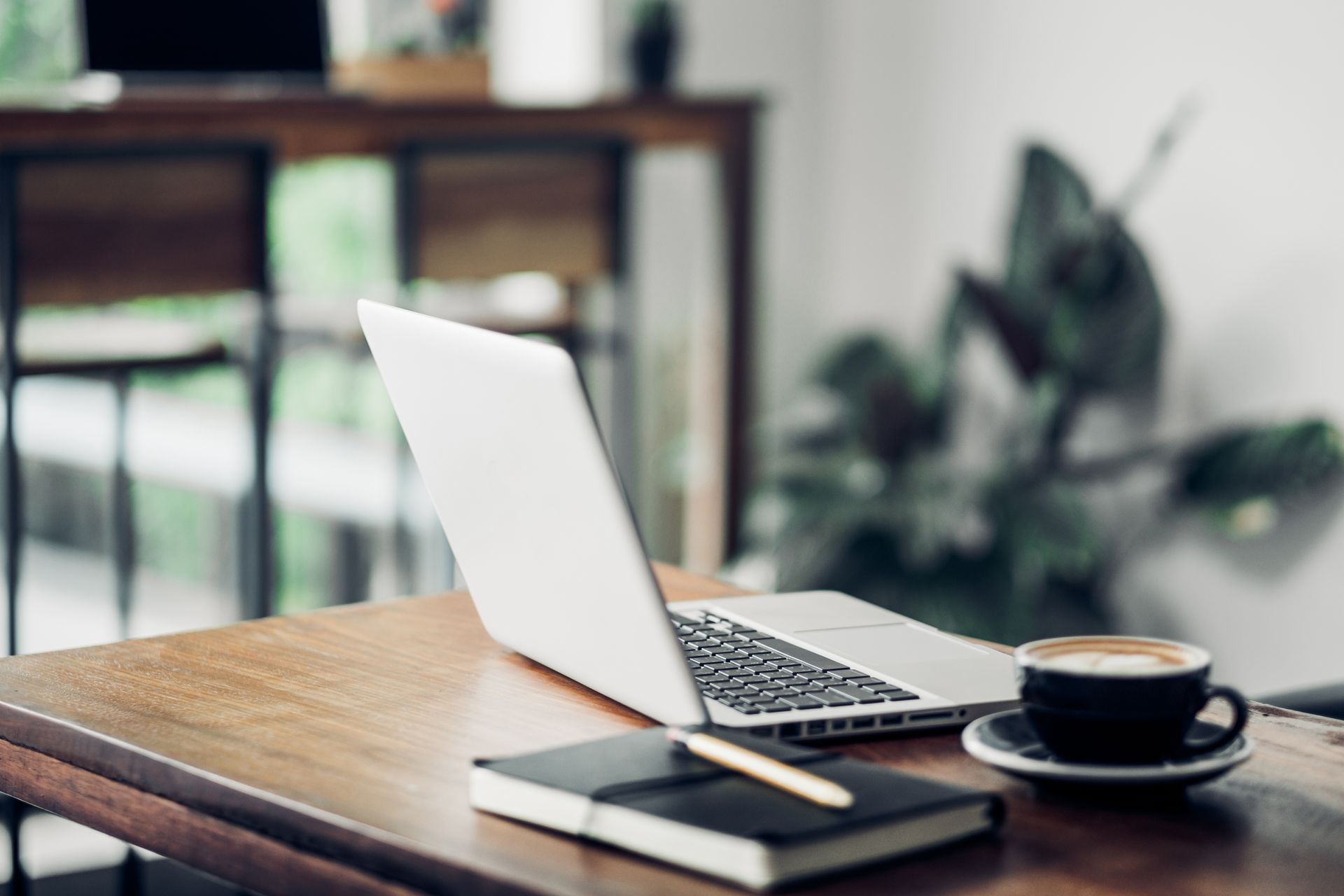 Bedroom with a desk, bed, and globe. Dark wood desk, black bedspread, white curtains, cream walls.