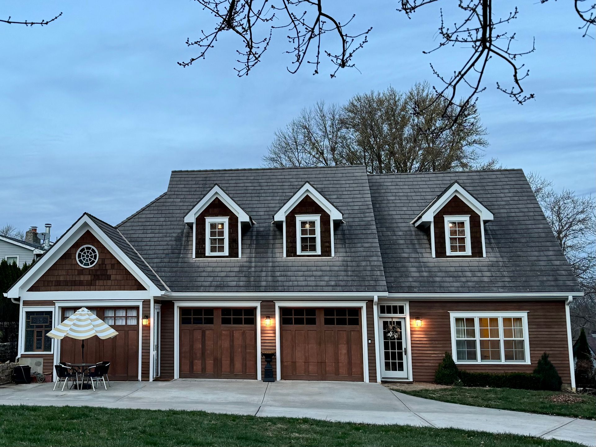 A large house is lit up at night with a car parked in front of it.