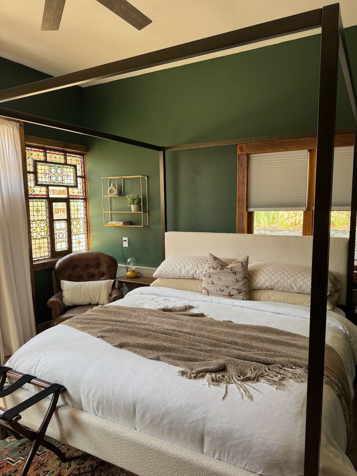 A bedroom with green walls and a canopy bed.
