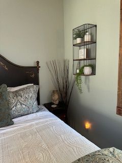 A bedroom with a bed , nightstand , shelves and a window.